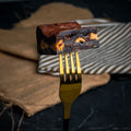 Close-up of a Nutty Buddy brownie held on a golden fork, showing its fudgy chocolate texture and thick Reese’s peanut butter layer.