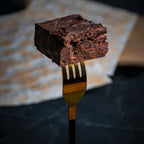 Close-up of a Sweet Surprise brownie held on a fork, showing its dense, fudgy texture made from sweet potatoes instead of flour.